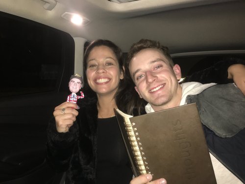 Two smiling riders holding the journal and the Jim bobblehead