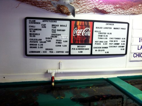 Lobster pound menu board above a lobster tank