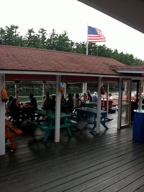 Covered deck with picnic tables and an American flag by the water