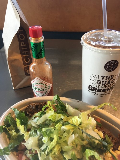 Chipotle burrito bowl with Tabasco and a drink