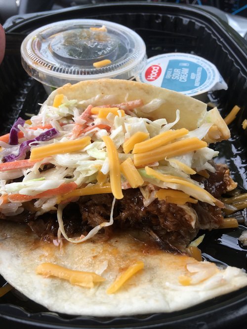 Soft taco with pulled meat, slaw and cheese in a takeout tray