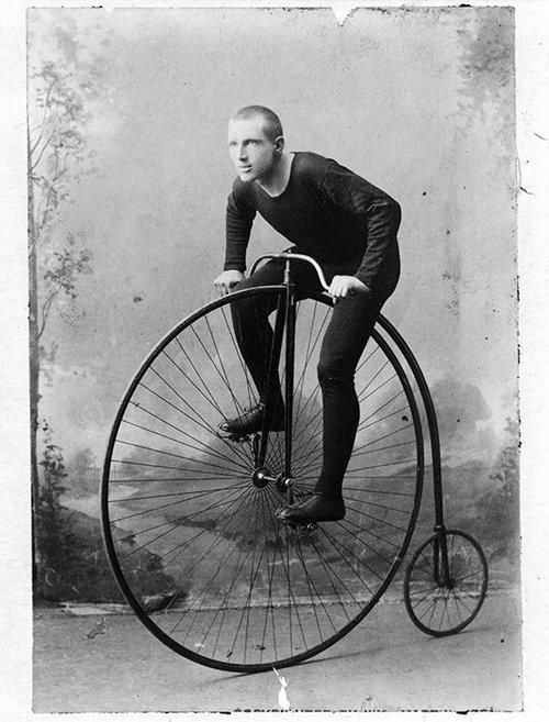 Man posing on a high-wheel bicycle