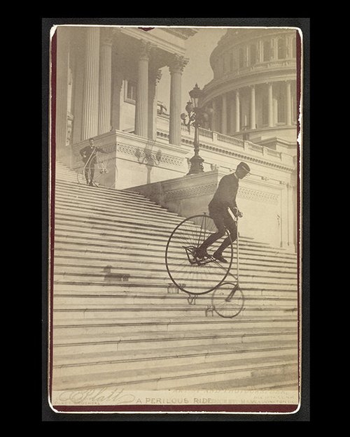 Rider coming down the U.S. Capitol steps on a high-wheel bicycle