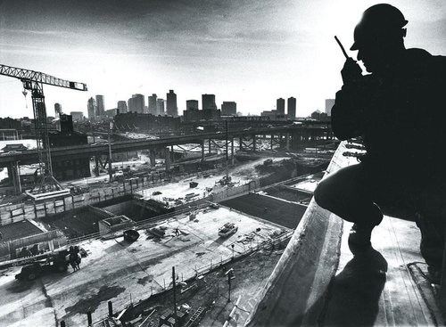 Silhouette of a construction worker above the Big Dig with the Boston skyline