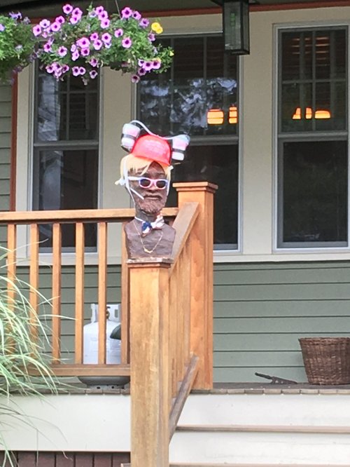 Figure of a man in a red cap and sunglasses on a porch railing