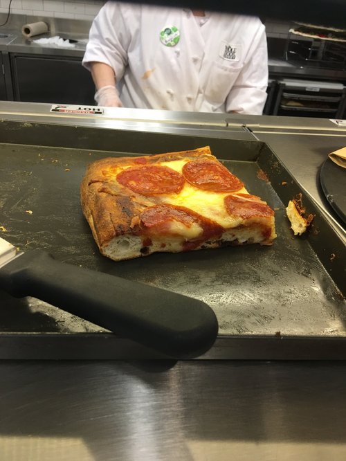 Square slice of pepperoni pizza being served