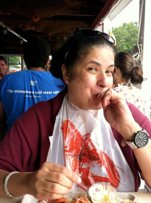 Woman in a lobster bib smiling over her lobster dinner
