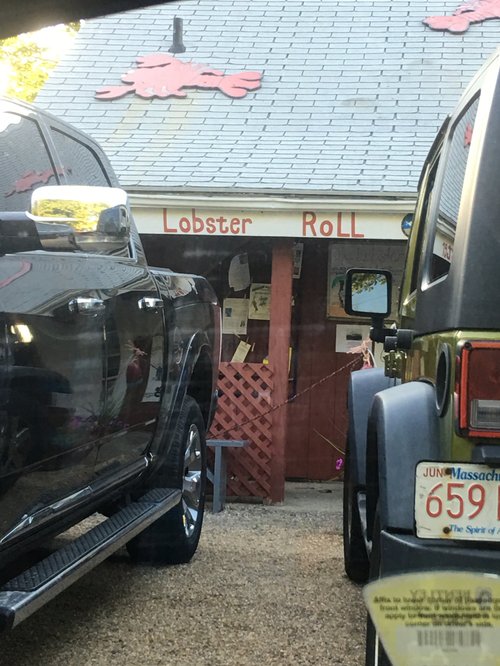 Lobster Roll shack seen between parked trucks