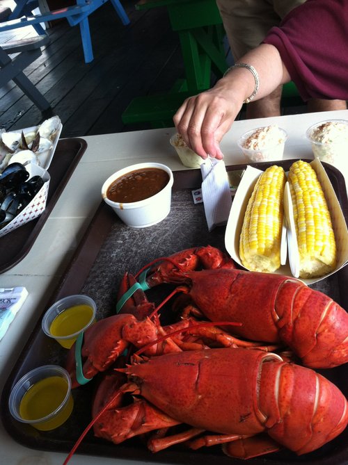 Boiled lobsters, corn and chowder on a tray