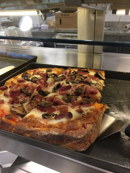 Square pizza with mushrooms and bacon on a sheet pan