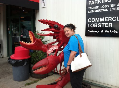 Woman posing with a giant lobster statue outside a Commercial Street seafood shop