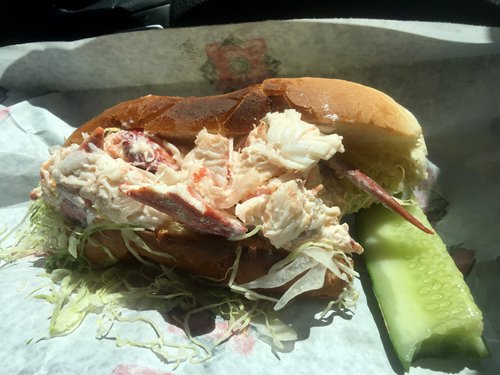Lobster roll with shredded lettuce and a pickle spear