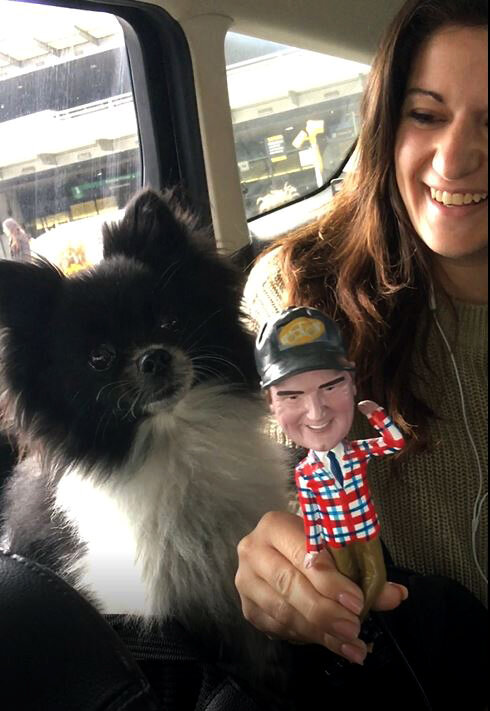 Smiling rider with her dog and the Jim bobblehead in the car