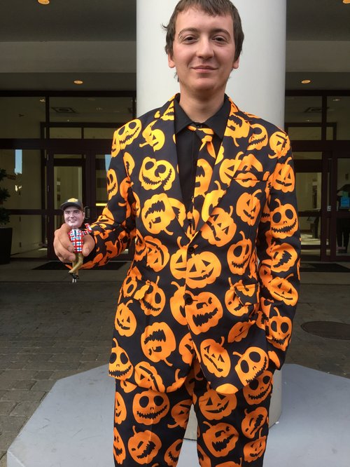 Young man in a jack-o'-lantern suit holding the Jim bobblehead