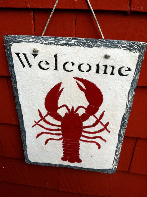 Welcome sign with a red lobster on a red shingled wall