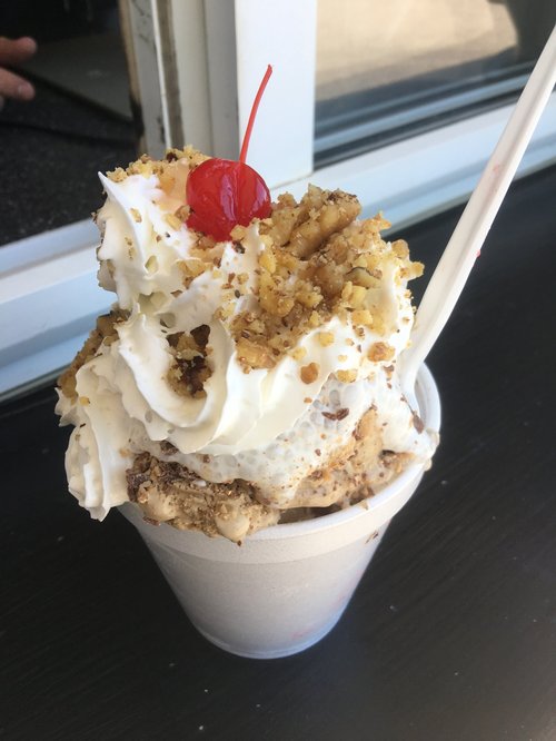 Ice cream sundae with whipped cream, nuts and a cherry